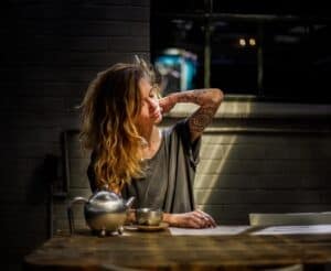 אישה עם כאבי צוואר, יושבת ליד שולחן עם כוס קפה